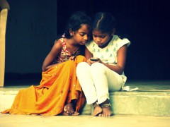 2 curious kids peering into a cell phone.